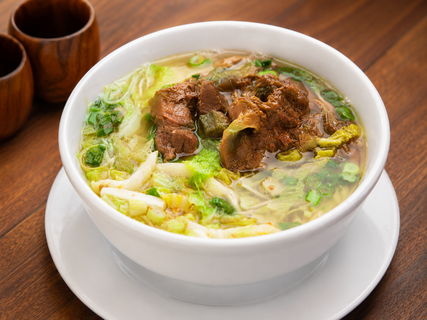 Bowl of Filipino-Chinese mami noodle soup with braised beef and greens